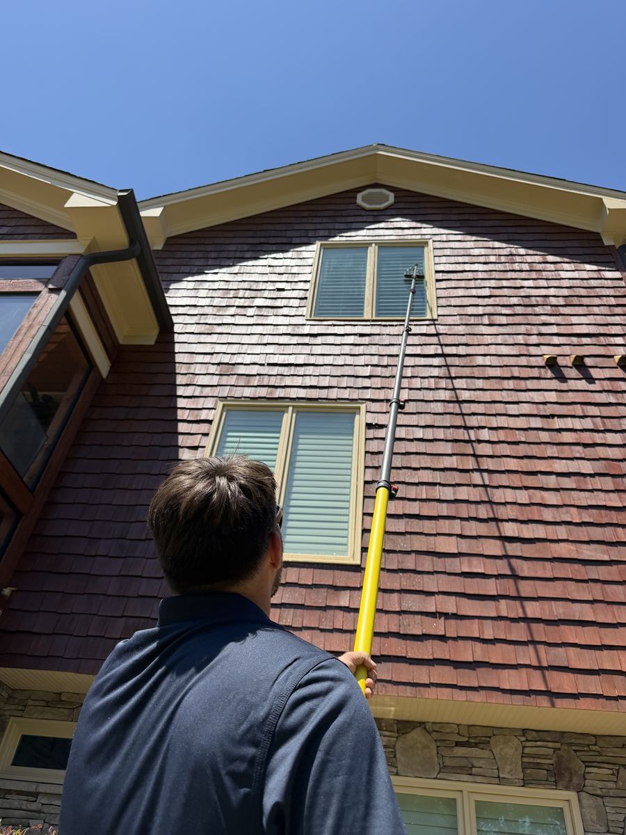 Piedmont Exterior technician cleaning second-story windows with water-fed pole system