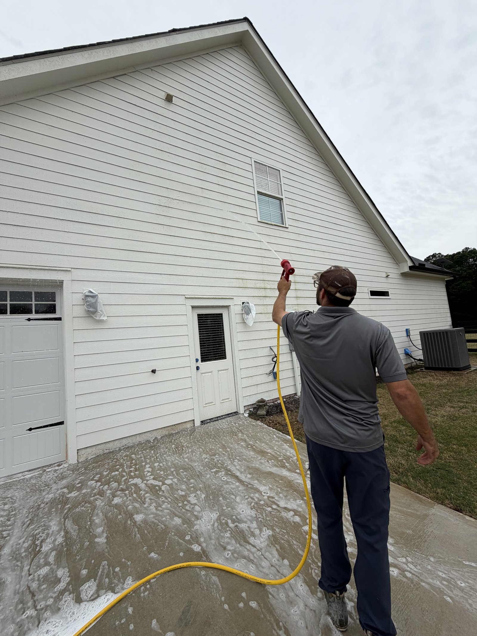 Trey applying soft wash solution to dirty siding