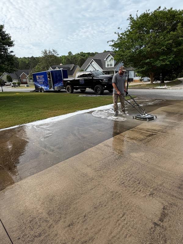 Trey cleaning driveway with surface cleaner showing before and after in same shot