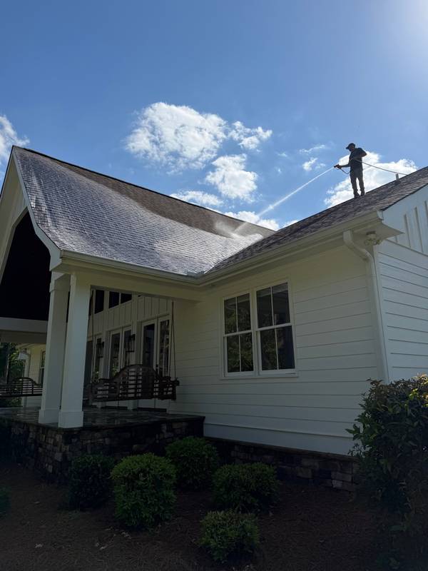 Trey standing on roof applying soft wash solution to residential home in Northeast Georgia